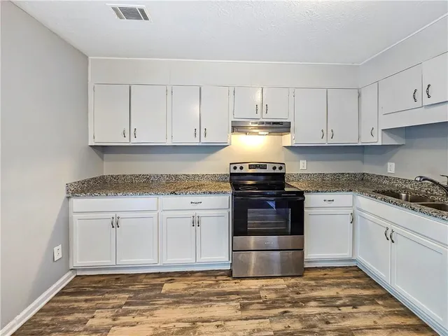 a kitchen with granite countertop white cabinets and stainless steel appliances