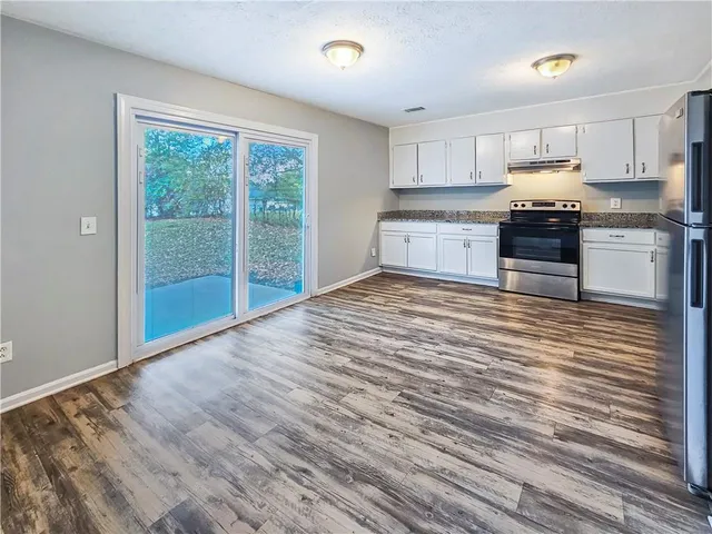 a kitchen with granite countertop a stove a sink and a refrigerator