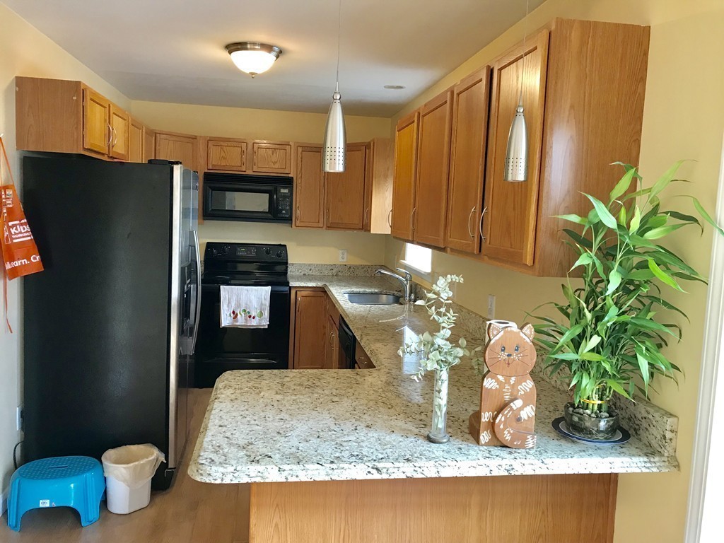 167 Orient Street Worcester, MA 01604 - Photo 10 of 29 a kitchen with a refrigerator a stove and a wooden cabinets