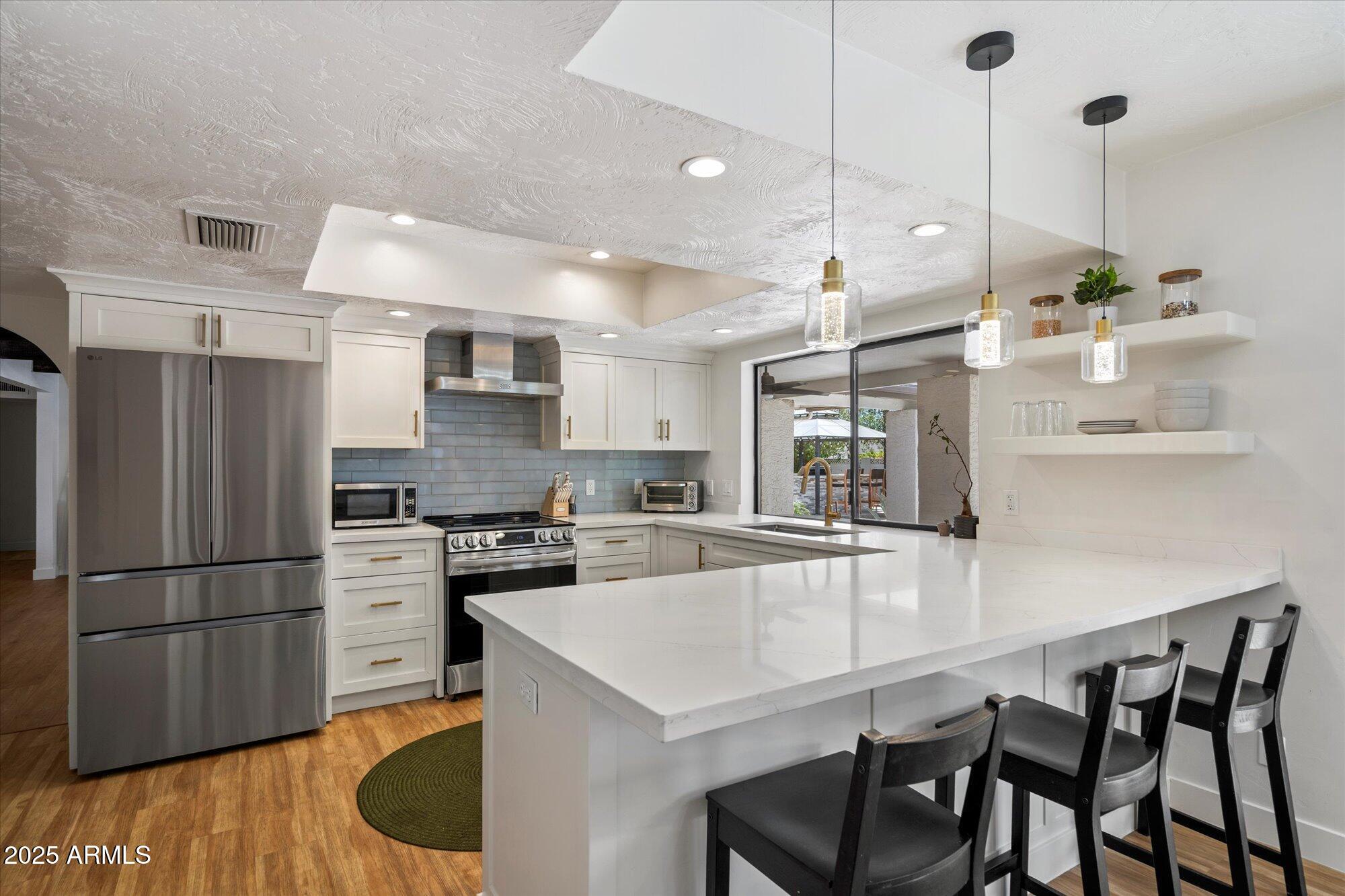 5701 East Charter Oak Road Scottsdale, AZ 85254 - Photo 6 of 27 a kitchen with kitchen island a large counter top space appliances and cabinets
