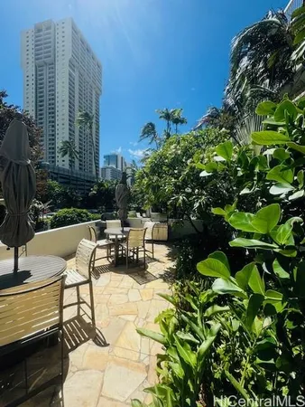a view of a patio with couches table and chairs under an umbrella with potted plants