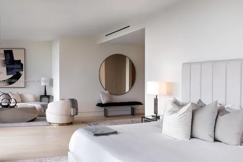 a bedroom with a bed a mirror and night stand with a potted plant