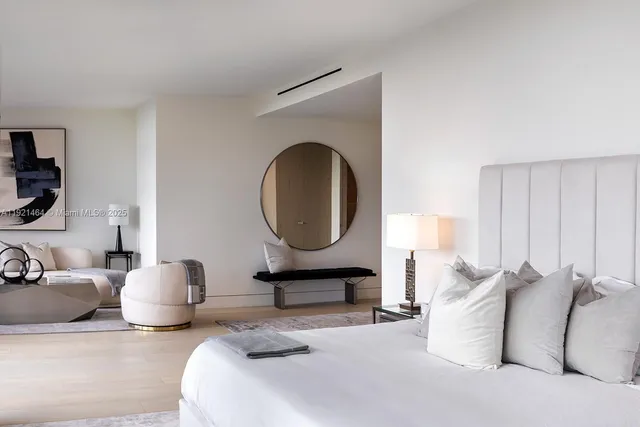 a bedroom with a bed a mirror and night stand with a potted plant