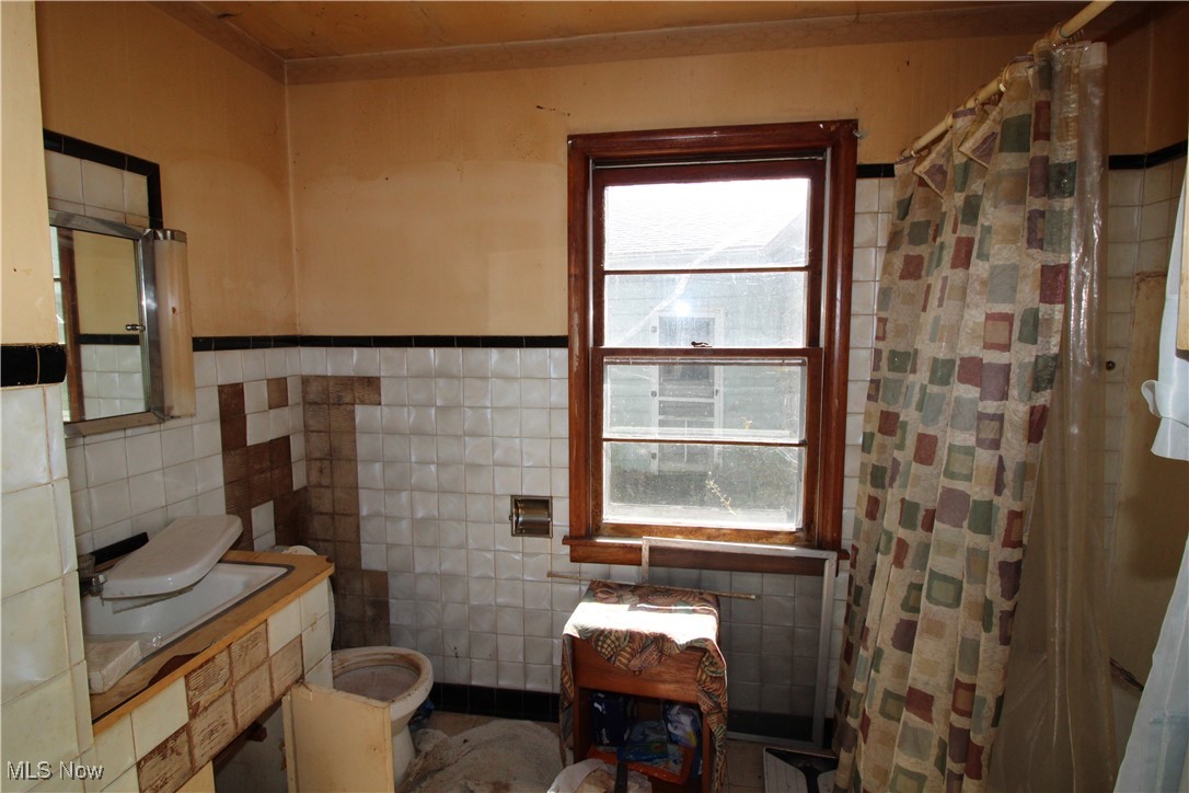 5084 West Fremont Road Port Clinton, OH 43452 - Photo 19 of 19 Full bathroom with tile walls, a shower with shower curtain, and a wainscoted wall