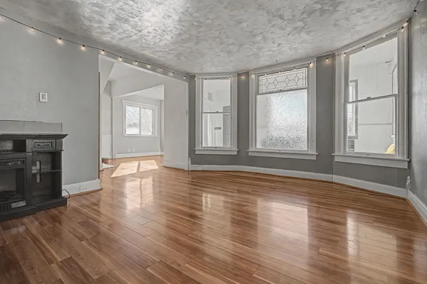 an empty room with wooden floor and windows
