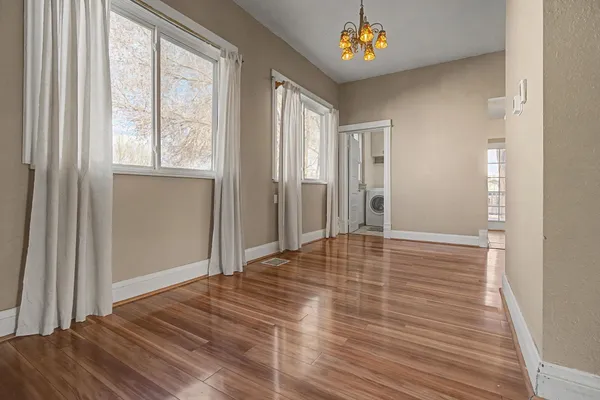 a view of empty room with wooden floor and fan