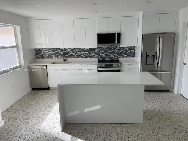 a kitchen with granite countertop a sink stove and refrigerator