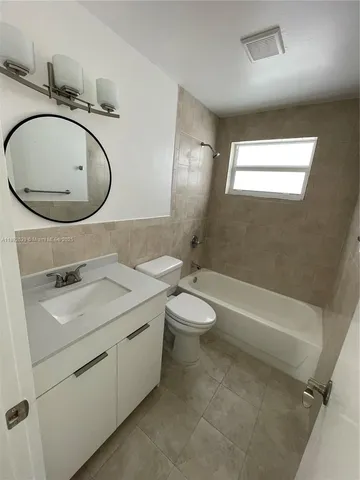 a bathroom with a granite countertop toilet sink and mirror