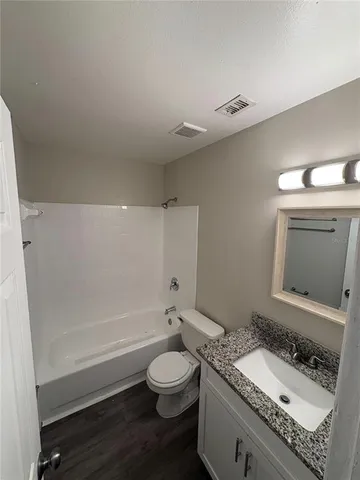 a bathroom with a granite countertop sink a toilet and shower