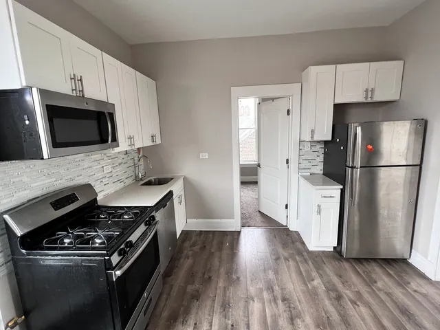a kitchen with wooden floor white cabinets and stainless steel appliances