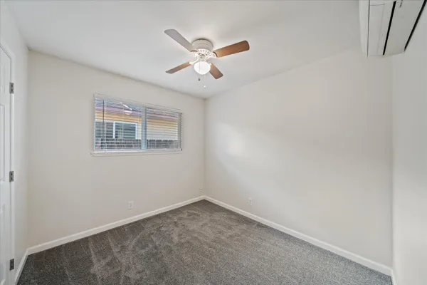 an empty room with ceiling fan and window