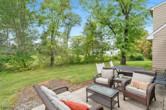 a view of a patio with couches table and chairs with garden and trees