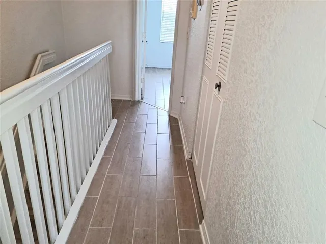 a view of a hallway with wooden floor and staircase