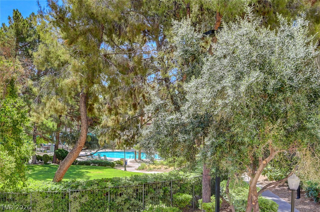 230 East Flamingo Road, Unit 106 Las Vegas, NV 89169 - Photo 26 of 66 A tranquil backyard vista unveils a shimmering pool and abundant green landscaping, perfect for leisurely afternoons.