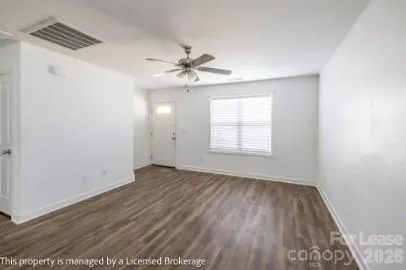 an empty room with wooden floor ceiling fan and windows