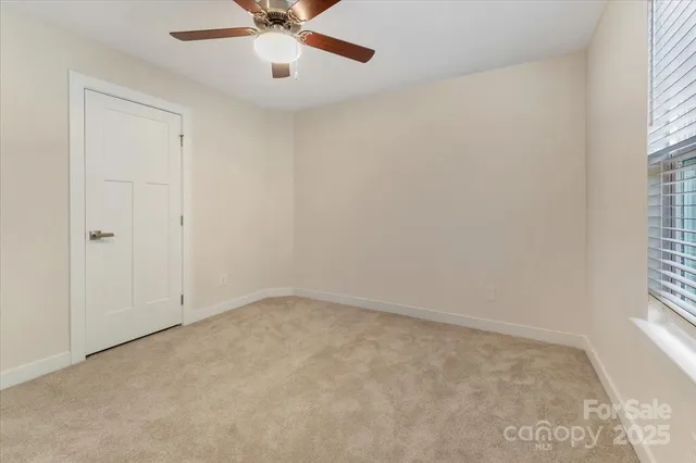 an empty room with a window and a fan