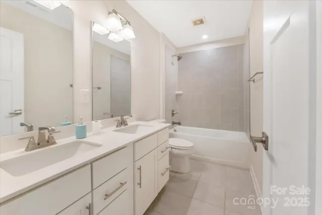 a bathroom with a double vanity sink toilet mirror and shower