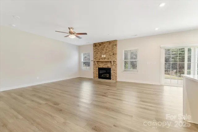 an empty room with wooden floor fireplace and windows