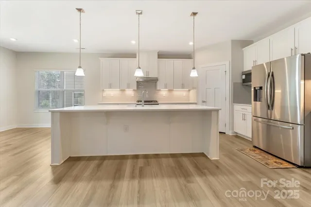 a kitchen with kitchen island a counter top space wooden floor and appliances