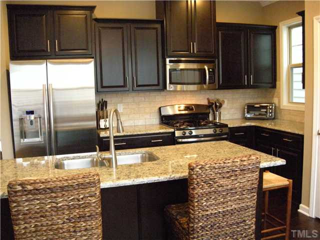 1326 Rodessa Run Raleigh, NC 27607 - Photo 4 of 20 Cooking is a delight in this kitchen that offers stainless steel appliances, granite countertops, stone backsplash, and an oversized breakfast bar area for quick meals, casual snacks, or a cup of coffee. Kitchen