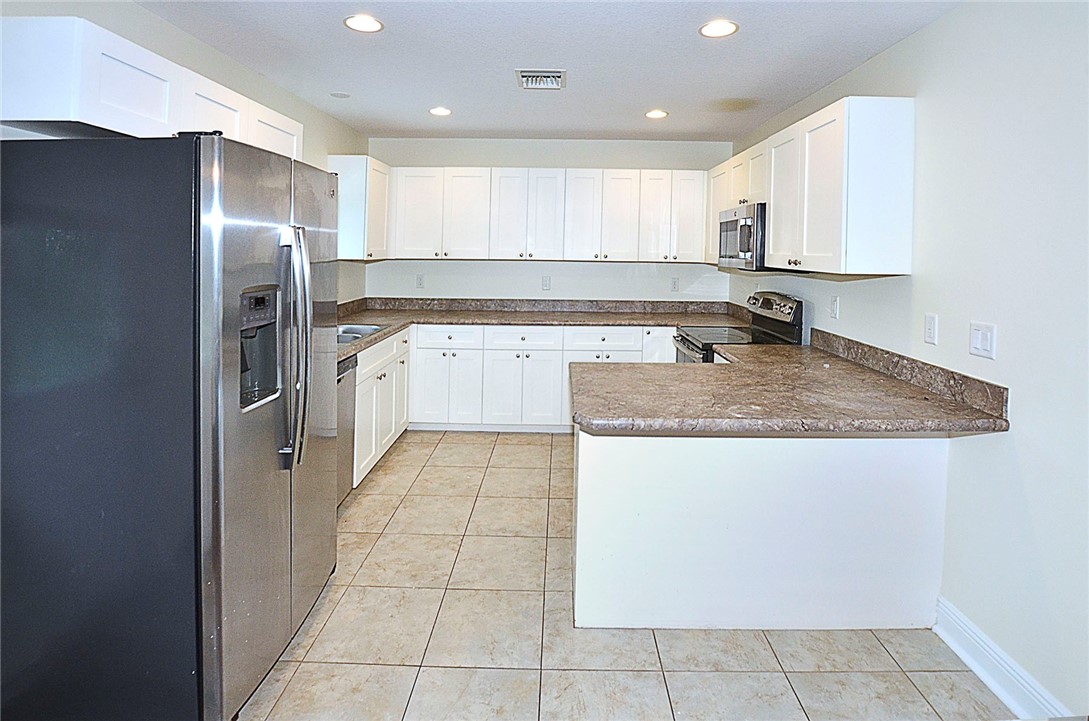4899 Kirby Loop Road Fort Pierce, FL 34981 - Photo 11 of 32 a kitchen with a sink a refrigerator and cabinets