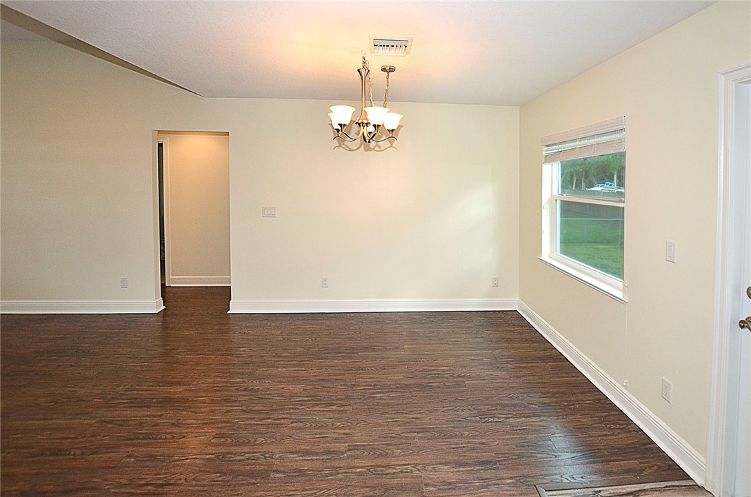 4899 Kirby Loop Road Fort Pierce, FL 34981 - Photo 6 of 32 wooden floor in an empty room with a window