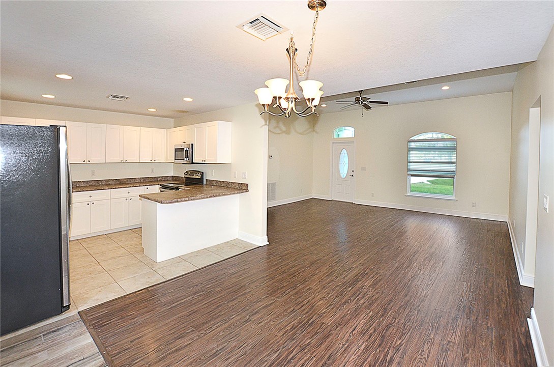 4899 Kirby Loop Road Fort Pierce, FL 34981 - Photo 7 of 32 a kitchen with stainless steel appliances granite countertop a stove a refrigerator and a wooden floor