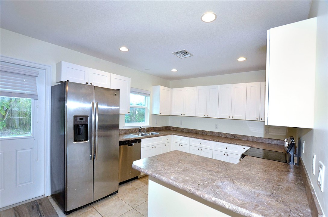 4899 Kirby Loop Road Fort Pierce, FL 34981 - Photo 8 of 32 a kitchen with a refrigerator and a sink