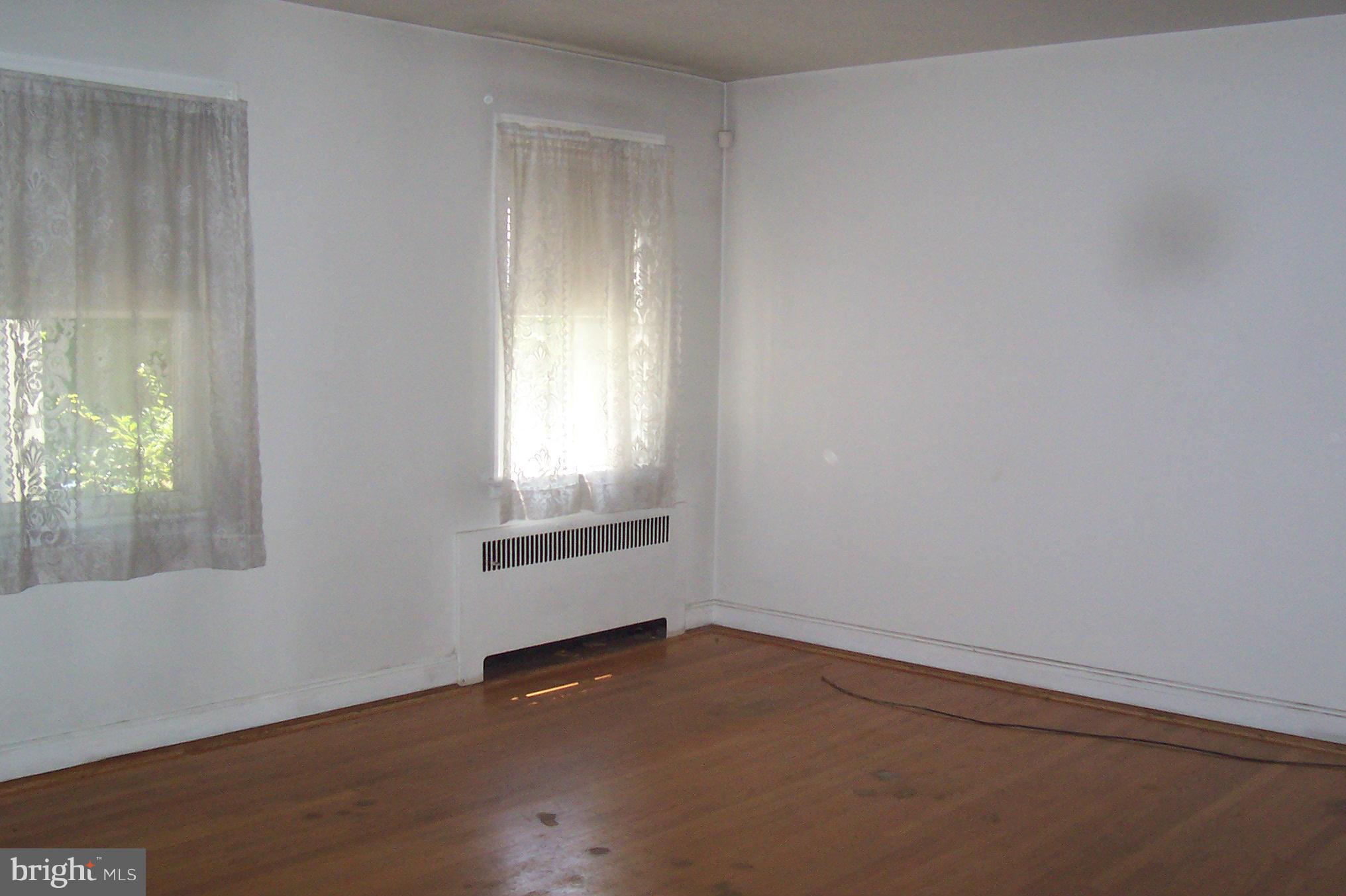 3704 Delverne Road Baltimore, MD 21218 - Photo 2 of 17 an empty room with wooden floor and windows