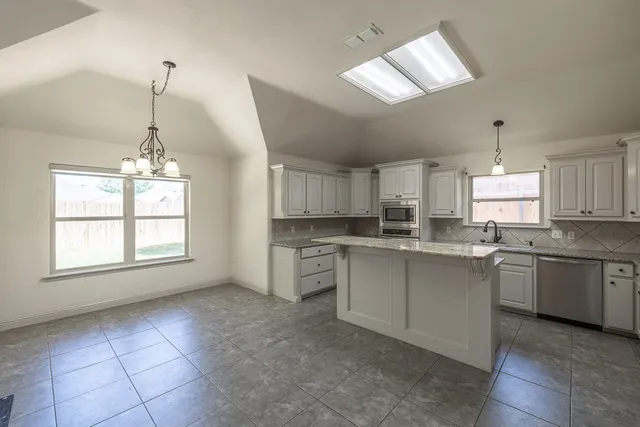 a kitchen with a stove a sink dishwasher a refrigerator and white cabinets with wooden floor