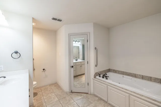 a bathroom with a tub sink and mirror