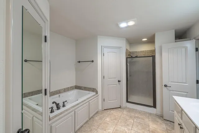 a bathroom with a tub shower and mirror
