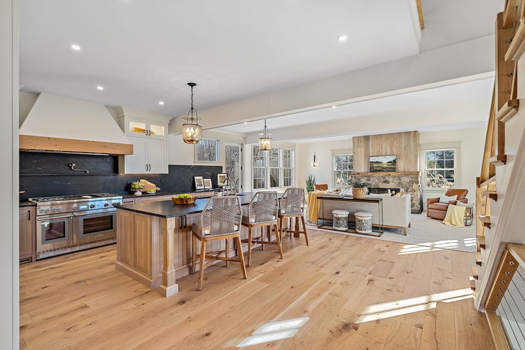 16 Hatch Farm Lane, Unit 16 Concord, MA 01742 - Photo 9 of 39 a kitchen with stainless steel appliances kitchen island granite countertop a stove top oven a sink a dining table and chairs with wooden floor