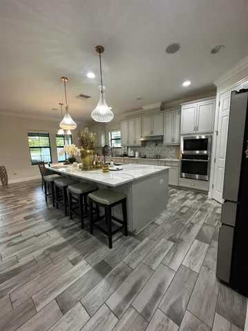 a view of a room with kitchen island stainless steel appliances wooden floor and living room view