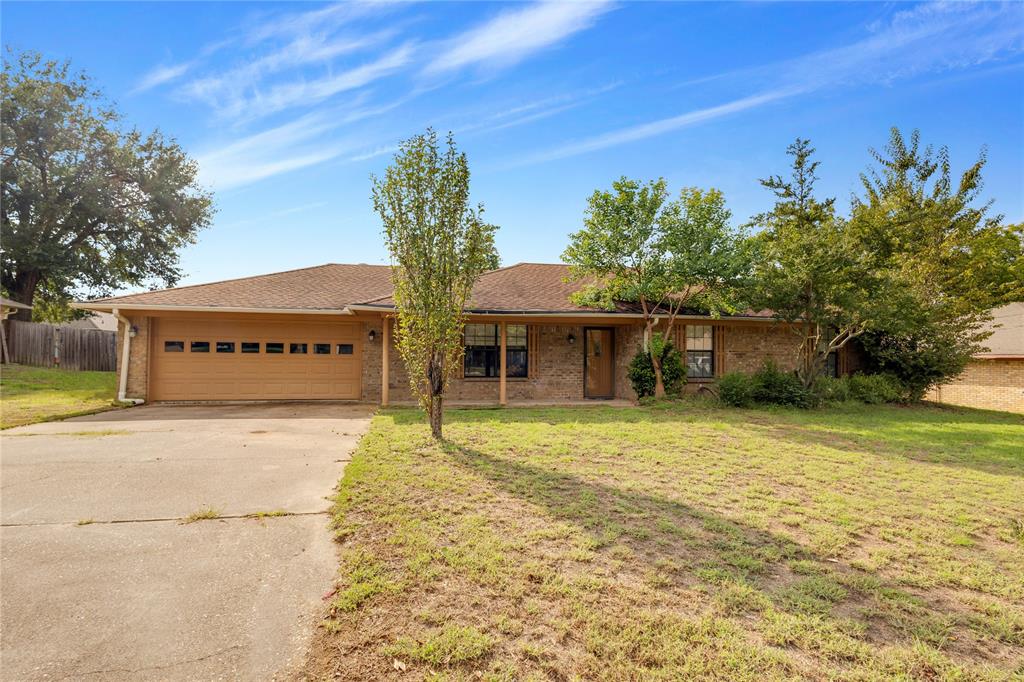 Single story home with concrete driveway, a garage, brick siding, and roof with shingles