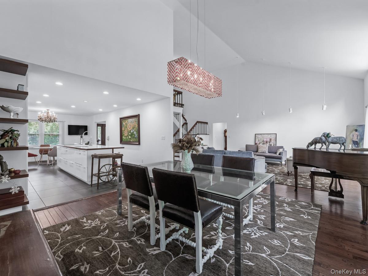 15 Fairway Circle South, Unit 15 Manhasset, NY 11030 - Photo 15 of 39 Dining area featuring a chandelier, dark wood-style floors, high vaulted ceiling, stairway, and recessed lighting