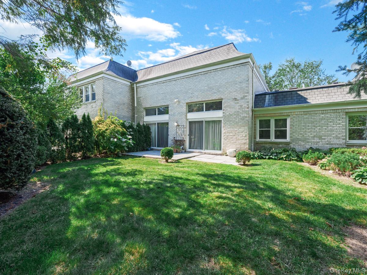 15 Fairway Circle South, Unit 15 Manhasset, NY 11030 - Photo 31 of 39 Back of house with brick siding, a lawn, and mansard roof