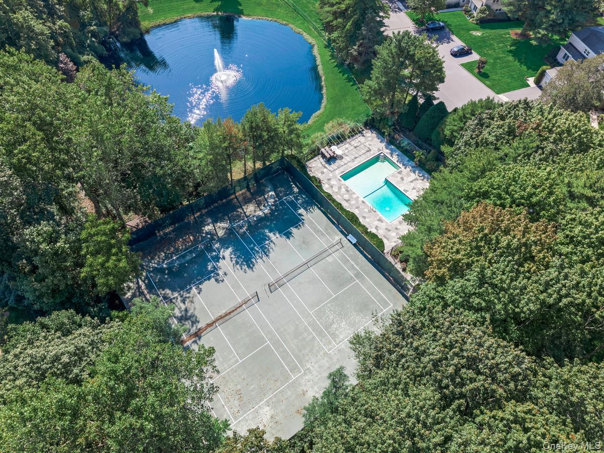 15 Fairway Circle South, Unit 15 Manhasset, NY 11030 - Photo 37 of 39 Drone / aerial view of a pool, tennis court, and pond with water fountain