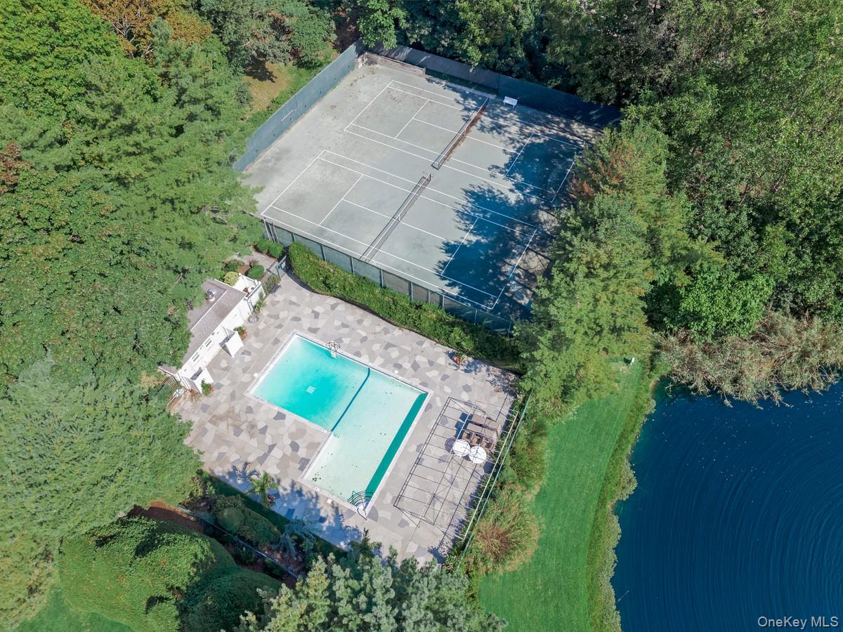15 Fairway Circle South, Unit 15 Manhasset, NY 11030 - Photo 38 of 39 Drone / aerial view of a pool, tennis court, and pond with water fountain