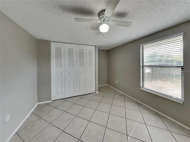 a view of an empty room with window and chandelier fan