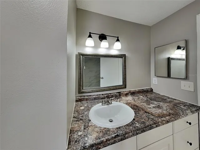 a bathroom with a granite countertop sink and a mirror