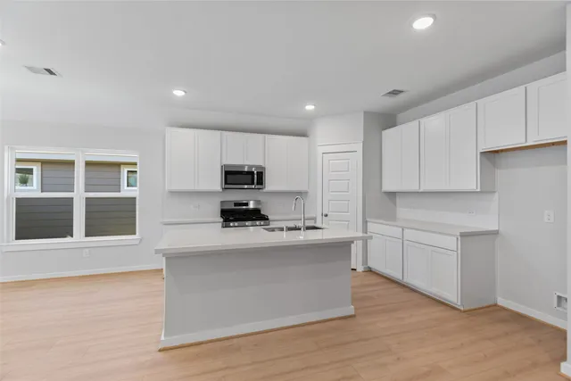 a large kitchen with stainless steel appliances granite countertop a stove a sink and white cabinets