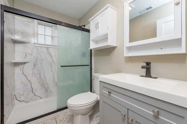 a bathroom with a sink a toilet and shower