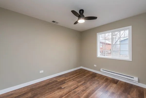 a view of empty room with wooden floor and fan