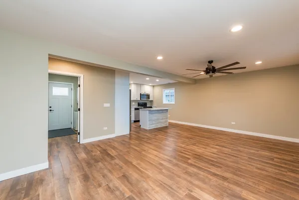 a view of a big room with wooden floor and a kitchen