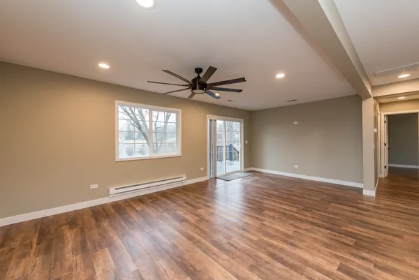 a view of an empty room with a window and wooden floor