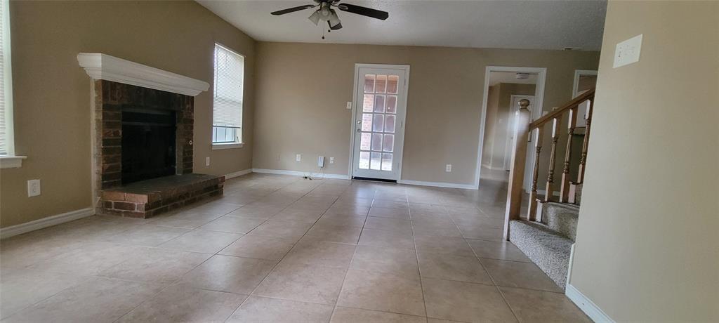 3031 Modella Avenue Dallas, TX 75229 - Photo 3 of 15 Unfurnished living room featuring light tile patterned floors, a fireplace, and ceiling fan