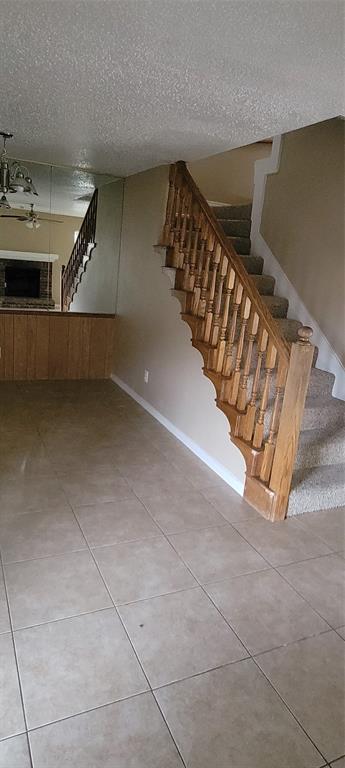 3031 Modella Avenue Dallas, TX 75229 - Photo 5 of 15 Stairway featuring a textured ceiling, tile patterned floors, and ceiling fan
