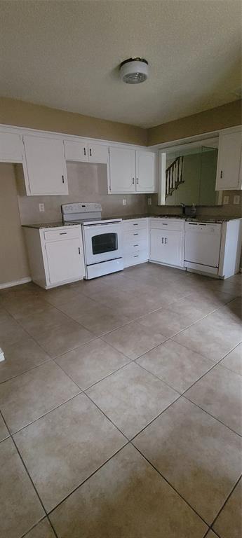 3031 Modella Avenue Dallas, TX 75229 - Photo 7 of 15 Kitchen featuring white appliances, white cabinets, a textured ceiling, and light tile patterned flooring