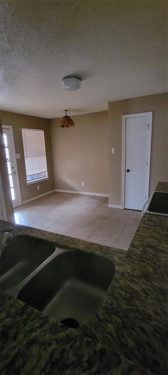 3031 Modella Avenue Dallas, TX 75229 - Photo 8 of 15 Kitchen with light tile patterned floors, a textured ceiling, and dark stone counters